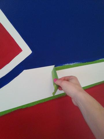 Peeling painter's tape off of the Montreal Canadiens mural painted by Adrienne of AboutMurals.ca