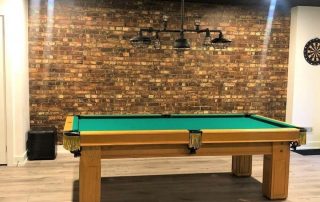 Brown Brick Wallpaper, as seen in this billiards room, features rustic looking red brick. Brick wallpaper from AboutMurals.ca.