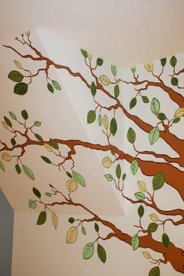Adrienne of AboutMurals.ca painted leaves on a slanted ceiling in a mural