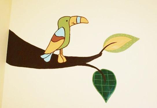 A rainforest mural featuring a toucan, inspired by crib bedding, and painted by Adrienne of AboutMurals.ca