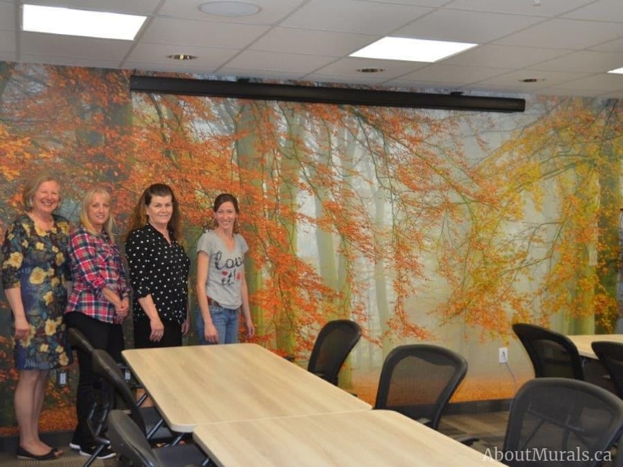 Autumn Season Wallpaper, as seen on the wall of Stedman Hospice in Brantford, ON, is a photo mural of orange trees arching over a leaf covered path leading towards a misty forest from About Murals.