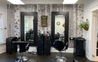 Birch Tree Forest Black and White Wall Mural, as seen in this hair salon, is a photo wallpaper of a black and white birch forest from About Murals.