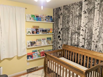 Black and White Birch Tree Wallpaper, as seen on the wall of this yellow nursery, is a photo wall mural of tall, modern trees in a forest from About Murals.