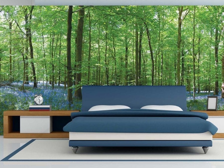 Bluebell Forest Wallpaper, as seen on the wall of this bedroom, features a bed of blue flowers under green spring trees from About Murals.