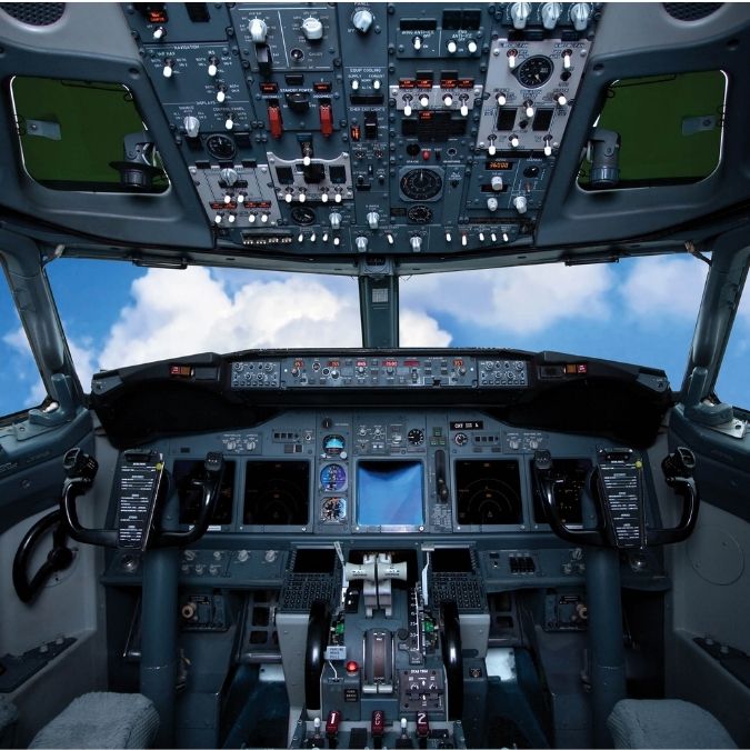 Cockpit Airplane Wallpaper for walls features a plane's control panel flying through a blue, cloudy sky from About Murals.