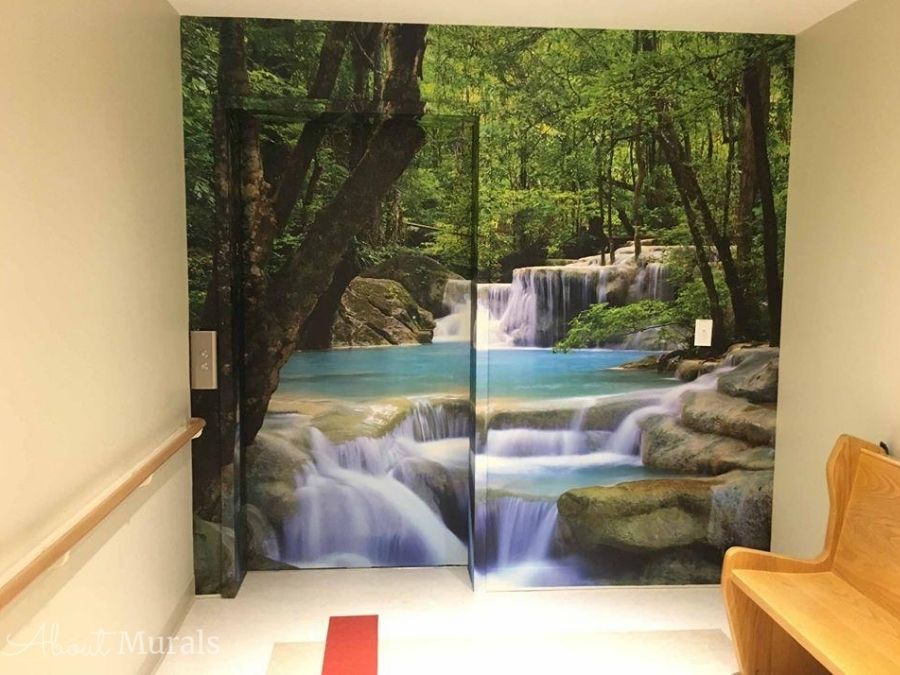 Erawan Waterfalls Thailand Wall Mural, as seen in this hospital, features a turquoise river flowing over rocks in a forest. Forest wallpaper sold by AboutMurals.ca.