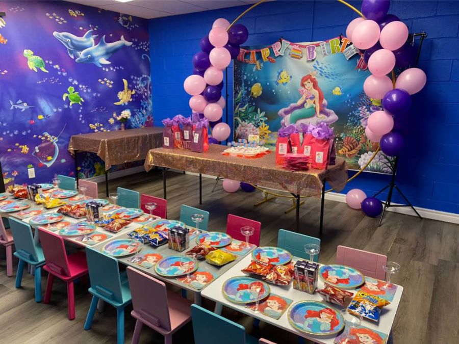 Fish Wall Mural, as seen in this little mermaid themed party room, is a kid’s fish themed wall mural with cartoon dolphins, sharks, fish and sea turtles under blue water from About Murals.