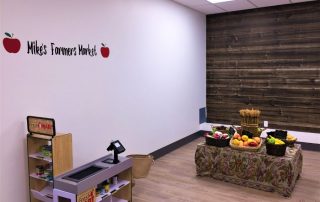 Horizontal Barn Wood Wallpaper, as seen in this kids grocery store play center, creates a rustic, textured look on walls with its realistic brown wooden planks. Wood wallpaper sold by AboutMurals.ca.