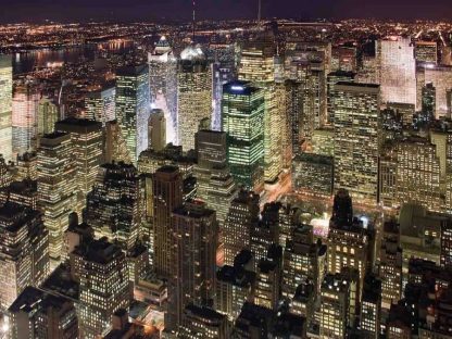 Manhattan at Night Wallpaper is a photo wall mural of tall buildings with lights on in New York City under a dark night sky from About Murals.