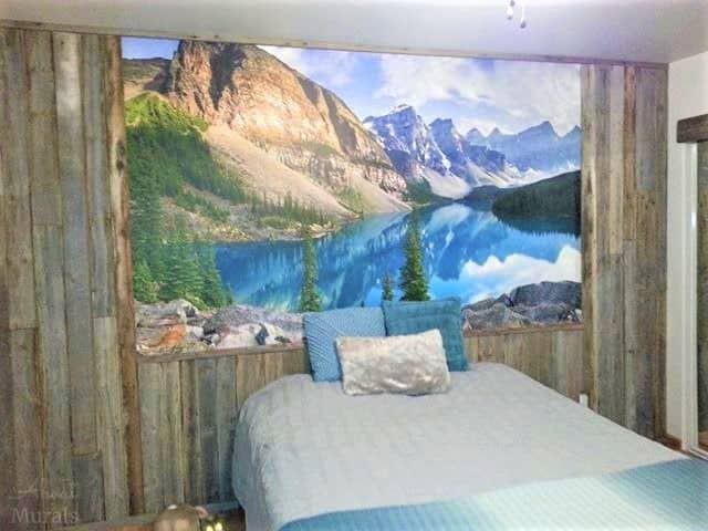 Moraine Lake Alberta Wall Mural, as seen in this bedroom, features towering mountains overlooking a turquoise lake. Forest wallpaper sold by AboutMurals.ca.