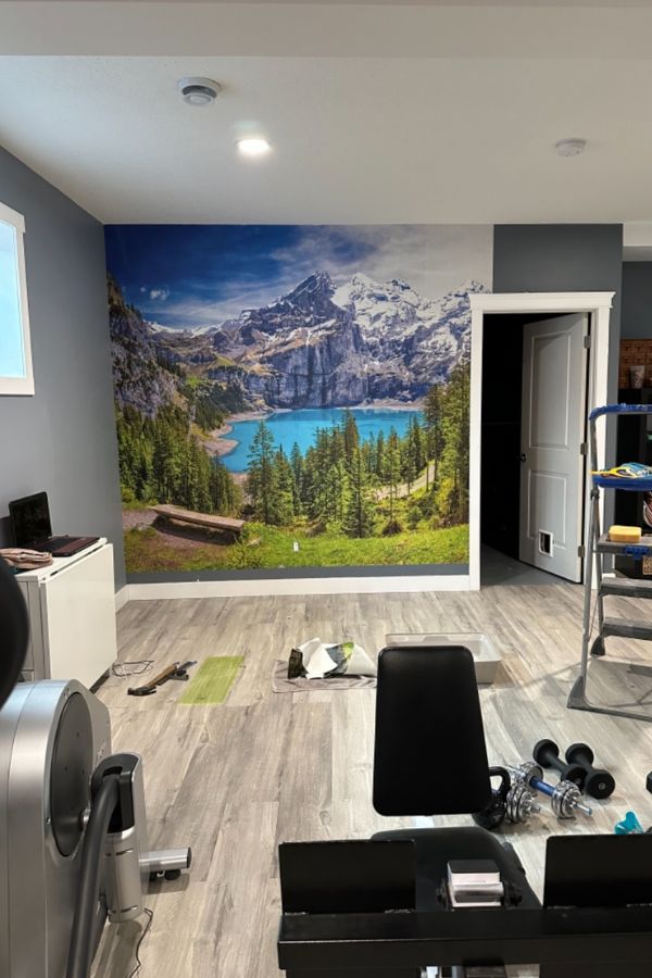 Moraine Lake Wallpaper, as seen on the wall of this home gym, is a mountain mural with an aqua blue lake in Canada from About Murals.