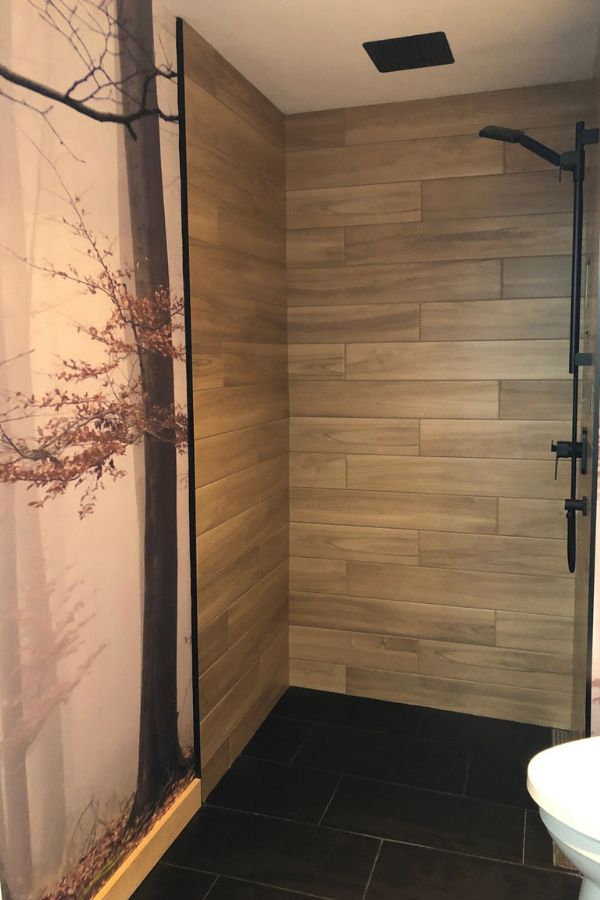 Morning Fog Wallpaper, as seen on the wall of this washroom, is a wall mural with a beautiful nature scene of trees in a gray forest from About Murals.