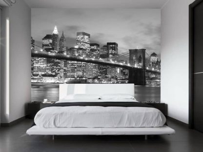 NYC Bridge Wallpaper, as seen on the wall of this bedroom, is a photo mural of a black and white Brooklyn Bridge in front of buildings and skyscrapers at night in New York City from About Murals.