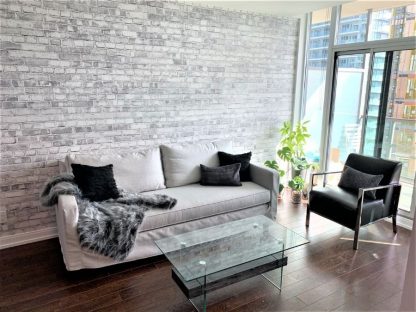Old Brick Wall Mural Light Black and White, as seen in Jackie Glass' client's condo, is a gray brick wallpaper with tons of realistic texture from About Murals.