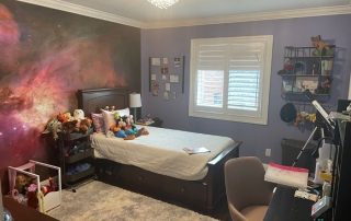 Orion Nebula Wall Mural, as seen in this bedroom, is a space wallpaper featuring clouds of purple and orange gas against a black star studded galaxy from About Murals.