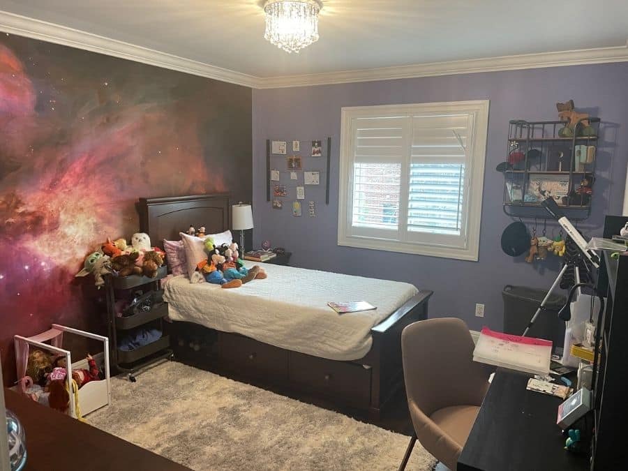 Orion Nebula Wall Mural, as seen in this bedroom, is a space wallpaper featuring clouds of purple and orange gas against a black star studded galaxy from About Murals.