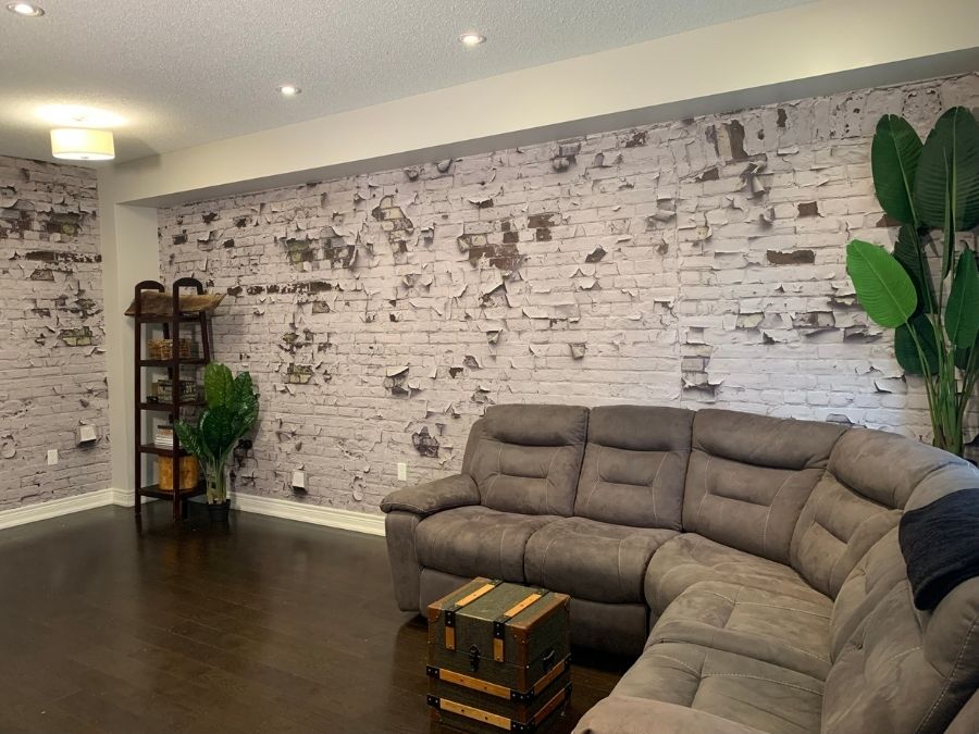Peeling Paint Brick Wallpaper, as seen on the wall of this living room, is a photo mural of white paint cracked on a brick wall from About Murals.