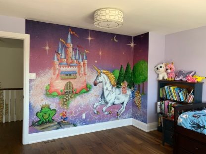 Princess Castle Wallpaper, as seen on the wall of this bedroom, is a unicorn mural with a pink castle, fairy and frog prince under a purple magical sky from About Murals.