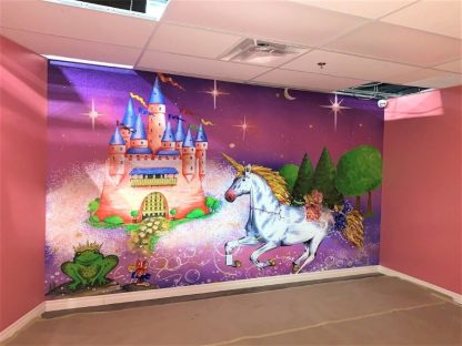 Princess Castle Wallpaper, as seen on the wall of this indoor playground, is a unicorn wall mural with a pink castle, fairies and frog from About Murals.
