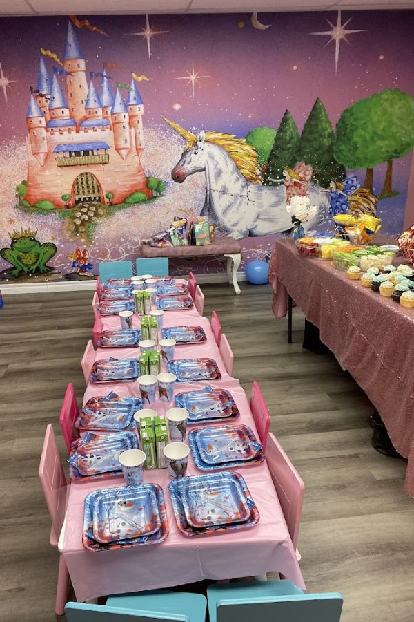 Princess Castle Wallpaper, as seen on the wall at Playtown Niagara behind birthday party tables, is a children’s wall mural of a pink castle and white unicorn from About Murals.