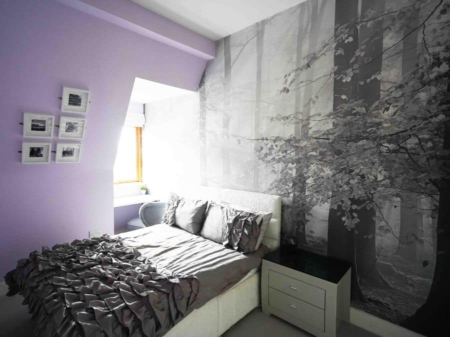 Sinfonia Della Foresta Black and White Wall Mural, as seen on the wall of this purple bedroom, is a forest wallpaper with sunbeams shining onto grey trees from About Murals.