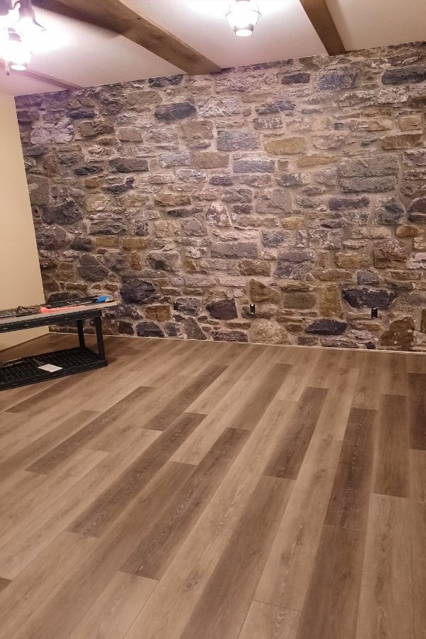 Stone Wall Mural, as seen in this basement, is a realistic stone wallpaper with gray, purple and mossy green rocks from About Murals.