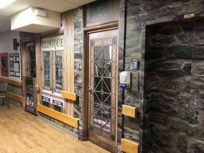 Stone Wall Mural, as seen in this retirement home on walls, a door and elevator, is a high resolution photo wallpaper of grey, blue and mossy green stones from About Murals.