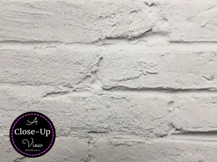 A close up view of a white brick wall mural shows all the texture in the bricks and mortar. Brick wallpaper sold by About Murals.