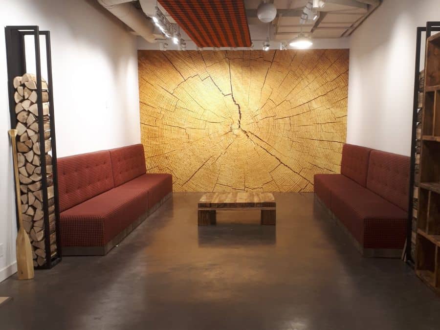 Wood Slab Wallpaper, as seen on the wall of this retail store, is a photo mural of a log slice exposing its rustic, textured annual rings from About Murals.