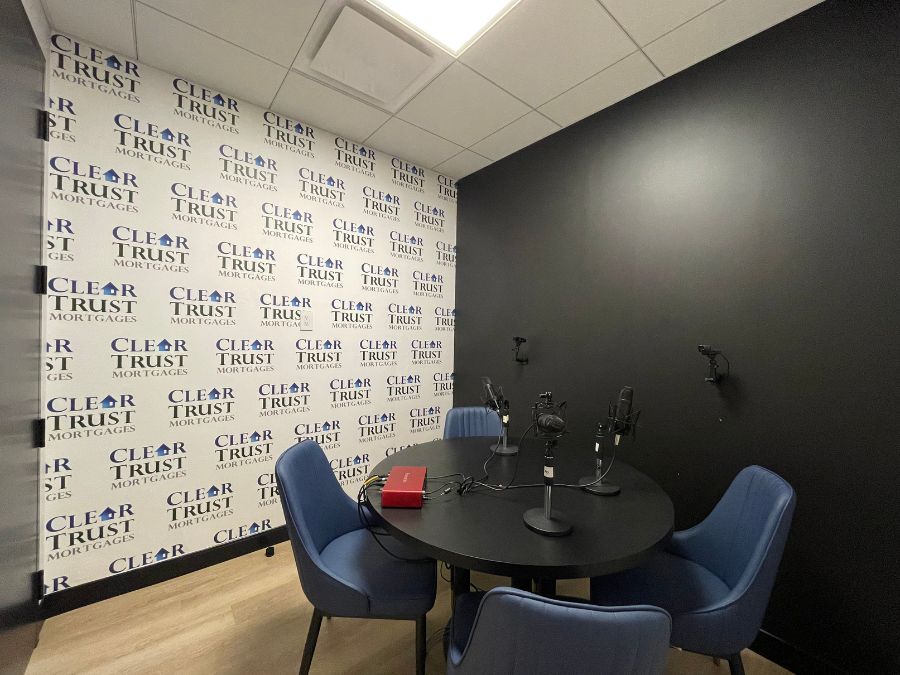 Custom logo wallpaper, as seen on the wall of this podcast room, features a repeating logo for Clear Trust Mortgages on a white background from About Murals.