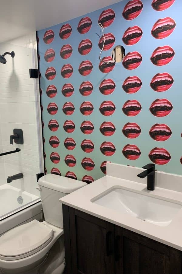 Custom Wallpaper, as seen on the wall of this bathroom, features colorful lips inspired by Britney Spears from About Murals.