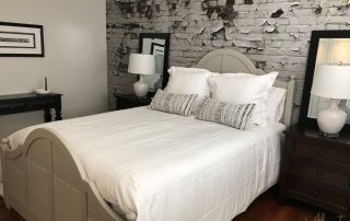A white brick wallpaper with peeling paint on the wall in a bedroom from AboutMurals.ca