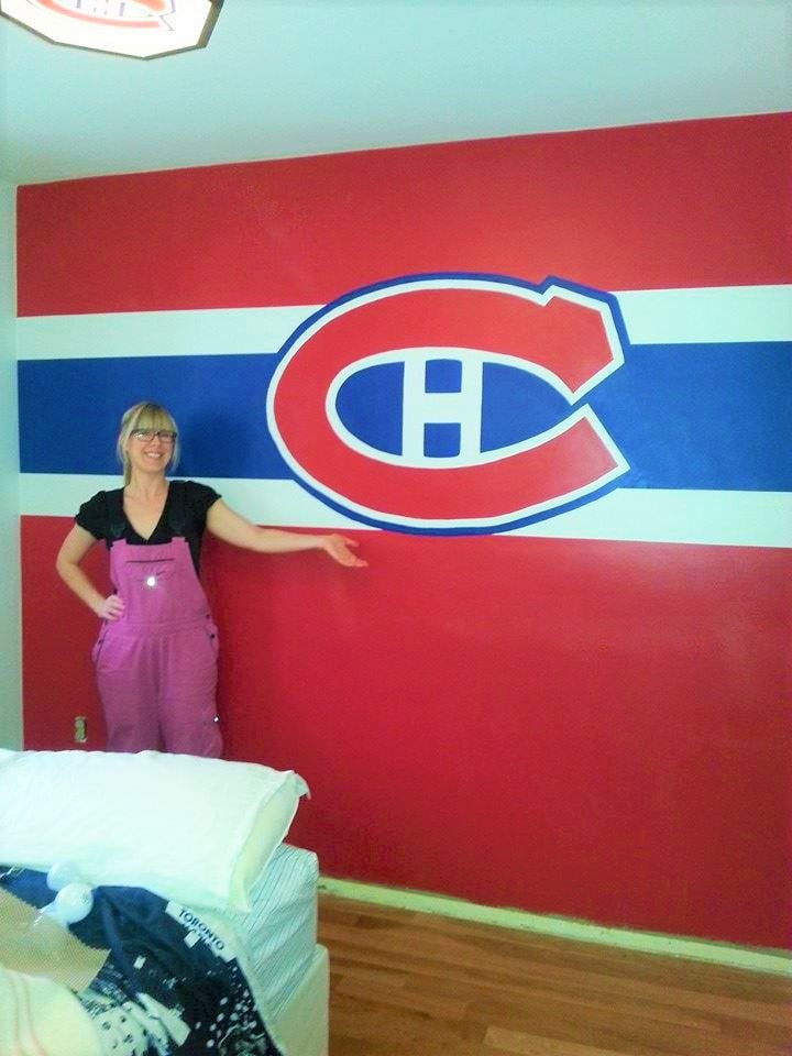 Muralist Adrienne stands next to the Montreal Canadiens mural she painted