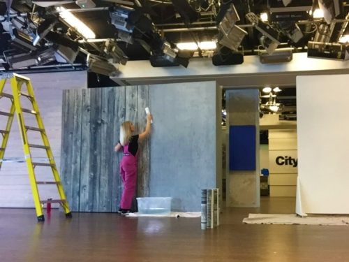 Adrienne of AboutMurals.ca offers wallpaper installation. She's seen here hanging a wood wallpaper on the Cityline set in Toronto.