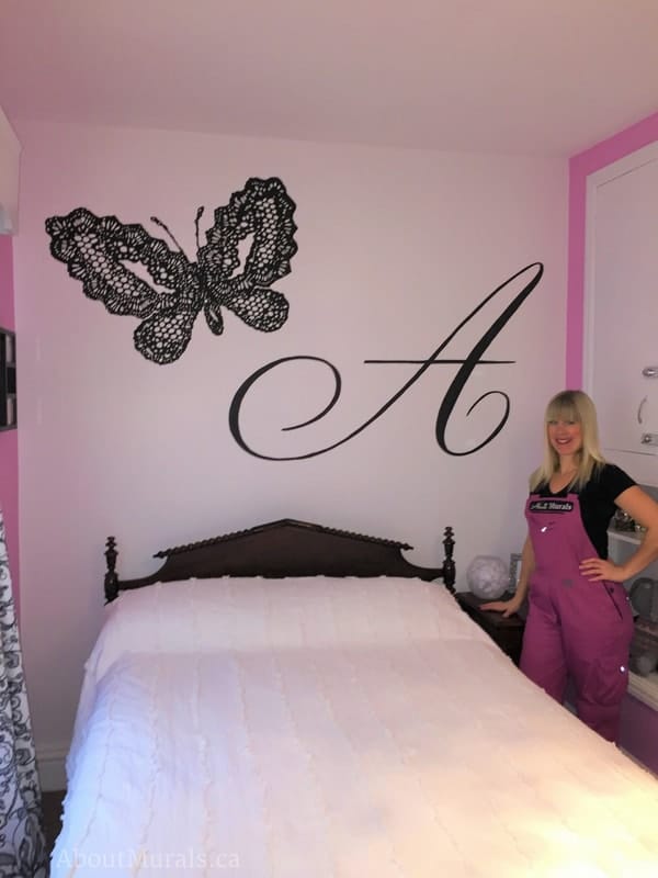 Adrienne of AboutMurals.ca stands next to the black butterfly mural she painted in her daughter's room