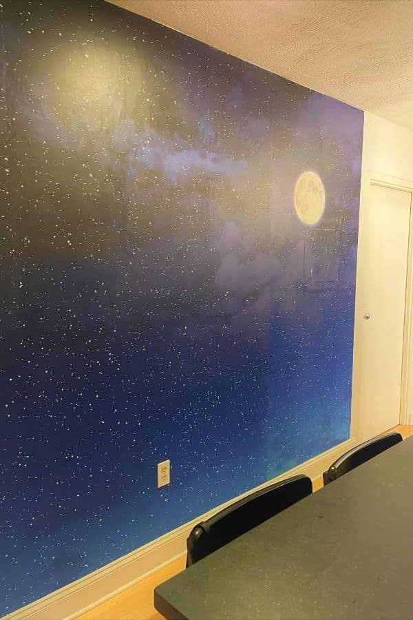 Night Sky Mural, as seen on the wall of this kitchen, is a removable wallpaper with stars and a moon in a dark sky from About Murals.