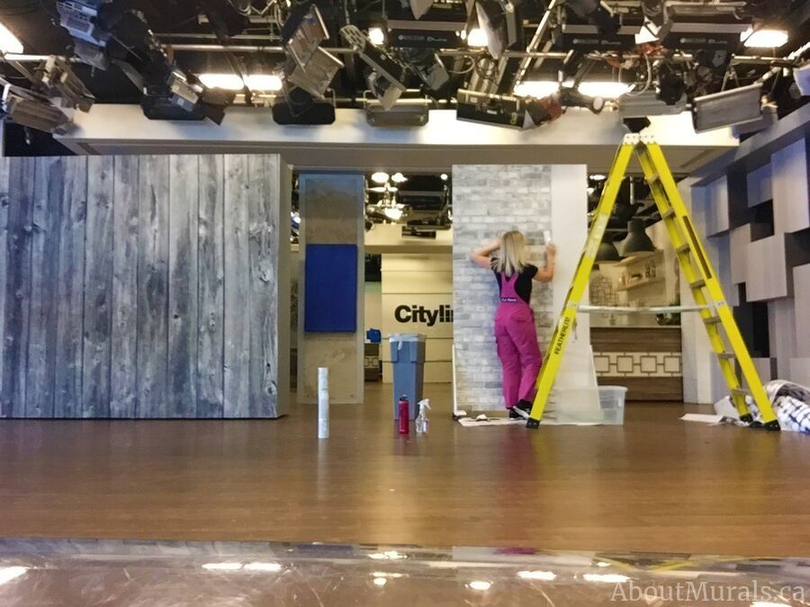 Adrienne of AboutMurals.ca hangs a removable brick wallpaper on set at Cityline