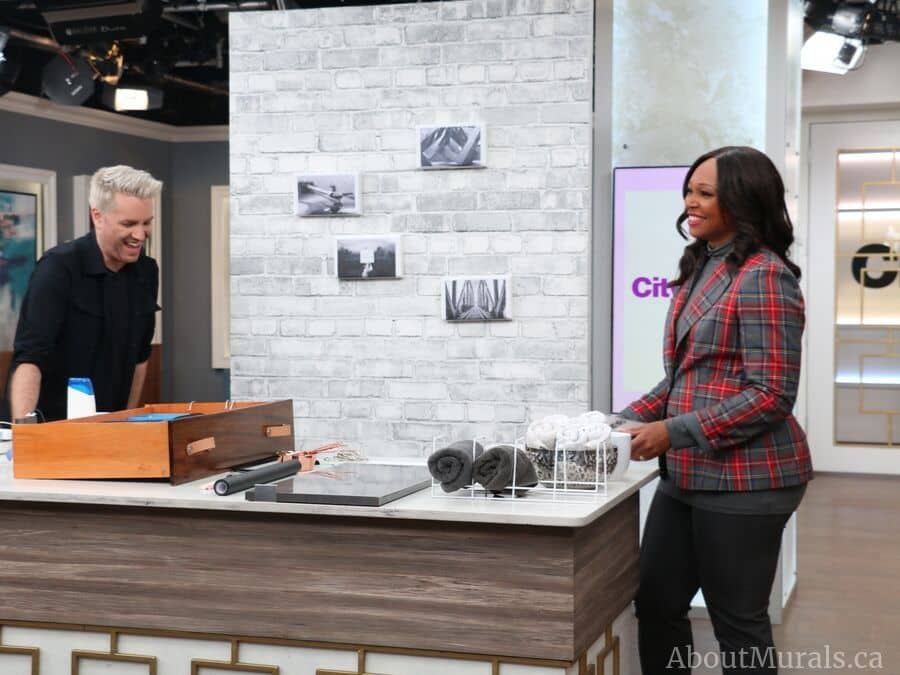 Christian Dare and Tracy Moore stand in front of a removable brick wallpaper from AboutMurals.ca on set at Cityline