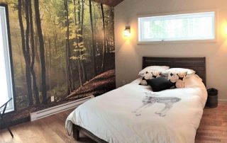 Sunbeams Wallpaper, as seen on the wall of this bedroom, features sun shining through trees in a forest. Forest wallpaper sold by AboutMurals.ca.