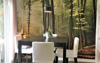 Sunbeams Wallpaper, as seen on the wall of this dining room, features sun streaming through trees in a forest. Forest wallpaper sold by AboutMurals.ca.