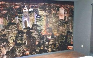 Birds Eye View of Manhattan Wallpaper, as seen on the wall of this bedroom, features skyscrapers in New York. Cityscape wallpaper sold by AboutMurals.ca.