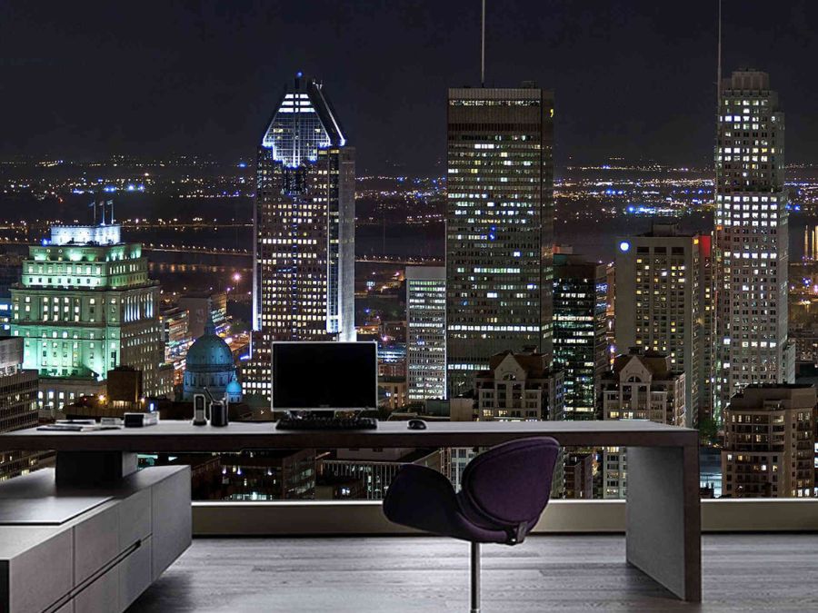Montreal Downtown Wallpaper, as seen on the wall of this office, is a photo mural of a Quebec skyline in downtown Montreal of lit up buildings under a dark night sky from About Murals.