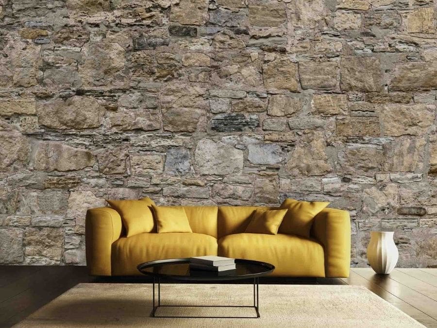 Castle Stone Wallpaper, as seen on the wall of this yellow living room, is a photo mural of realistic faux stones from About Murals.