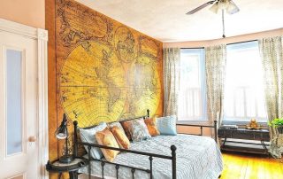 Old World Map Wallpaper, as seen on the wall of this bedroom, features an aged, vintage double hemisphere map. Map wallpaper sold by AboutMurals.ca.