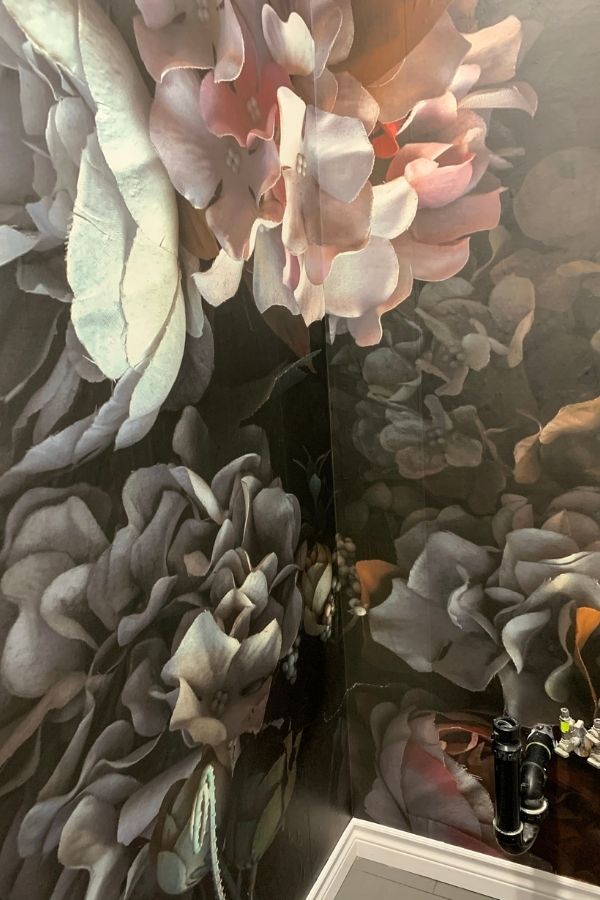 Dark Floral Wallpaper, as seen on the wall of this bathroom, features fabric peony and hydrangeas on a black background from About Murals.