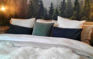 Foggy Forest Wallpaper, as seen on the wall of this master bedroom, features a grey misty fog settled among dark pine trees. Forest wallpaper sold by AboutMurals.ca.