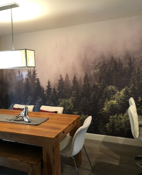 Foggy Forest Wallpaper, as seen on the wall of this dining room, is a photo mural of fog settling over coniferous trees from About Murals.