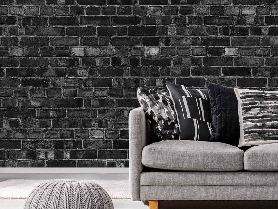Black Brick Wallpaper, as seen on the wall of this living room, features realistic, textured looking black and grey bricks from About Murals.
