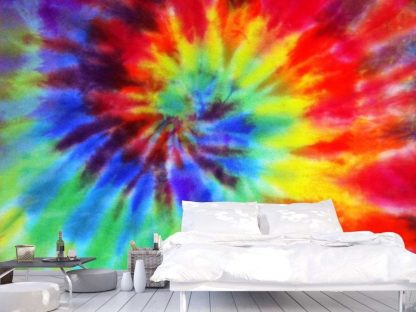 Rainbow Tie Dye Wallpaper, as seen on the wall of this bedroom, features a red, orange, yellow, green and blue spiral on a fabric texture from About Murals.