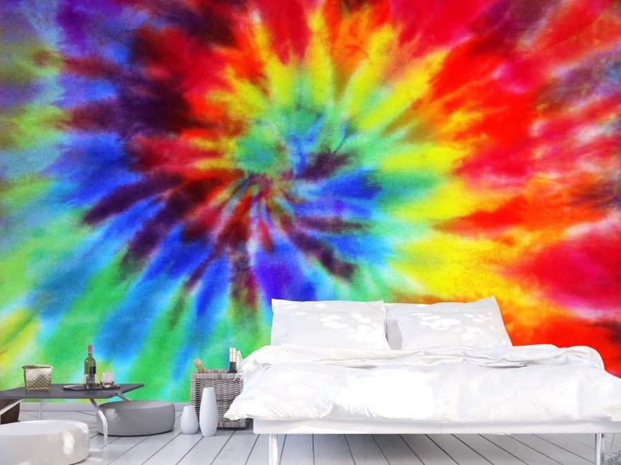 Rainbow Tie Dye Wallpaper, as seen on the wall of this bedroom, features a red, orange, yellow, green and blue spiral on a fabric texture from About Murals.